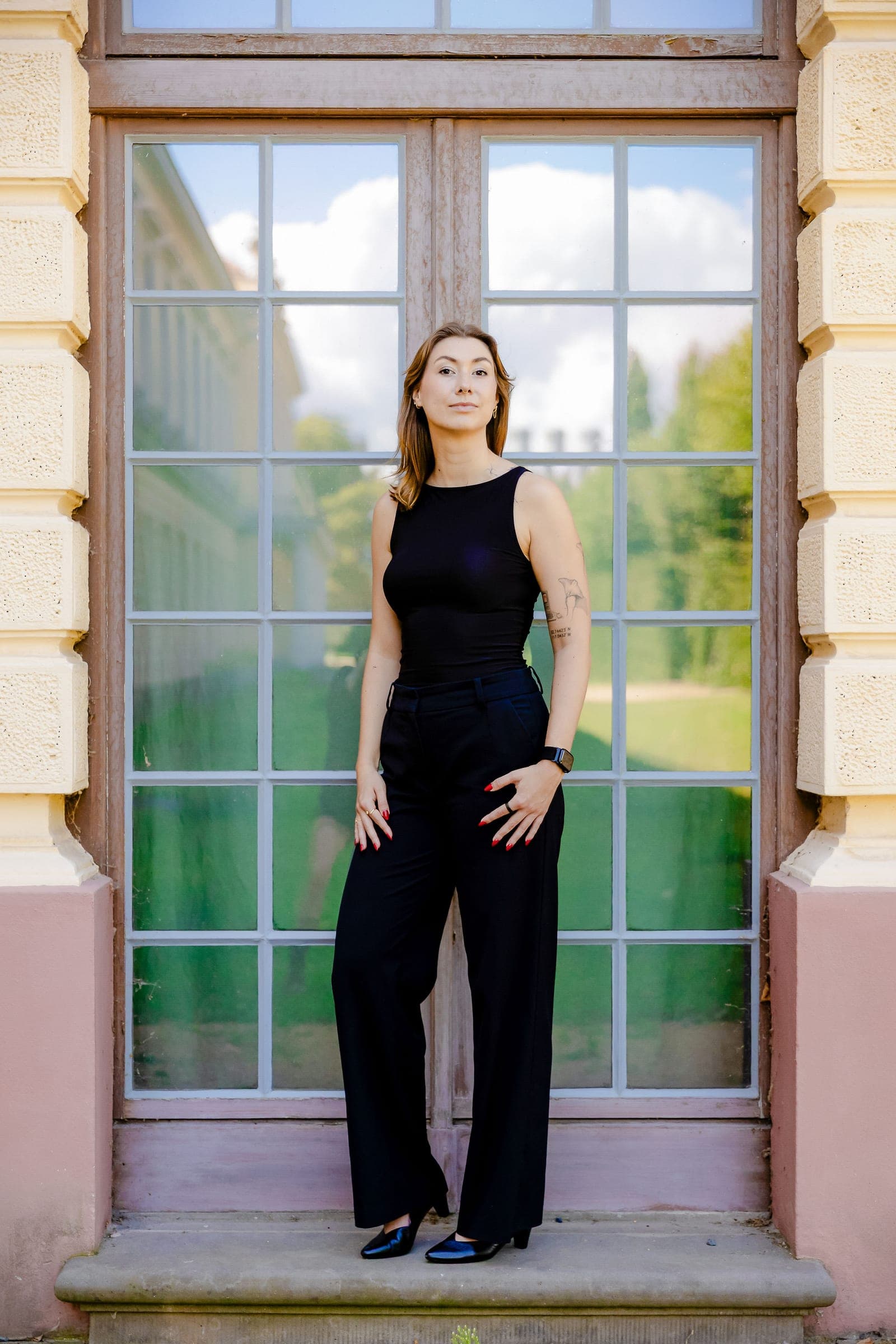 Victoria standing centred in the tall window of a pale stone building, framed by its white glazing bars.